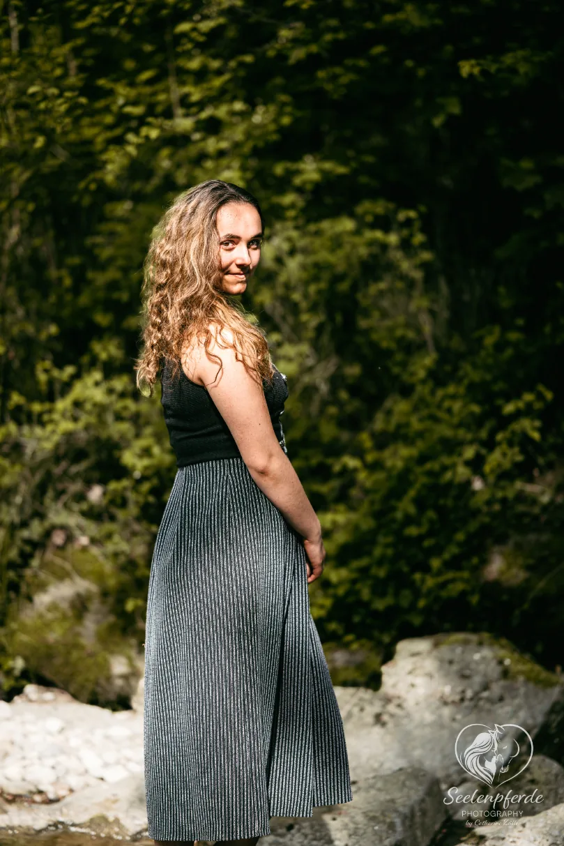 Frau im gestreiften Kleid dreht sich lächelnd zur Kamera, Modefotografie im Wald