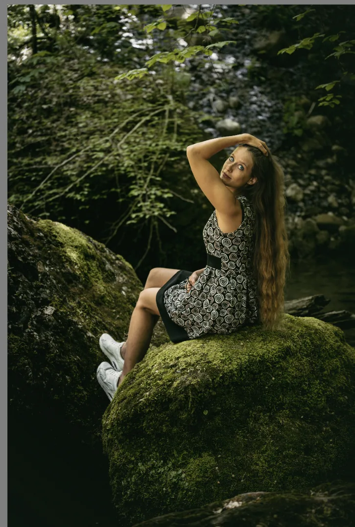 Porträtfotografie am Bach: Frau sitzt auf einem moosbewachsenen Stein im Wald
